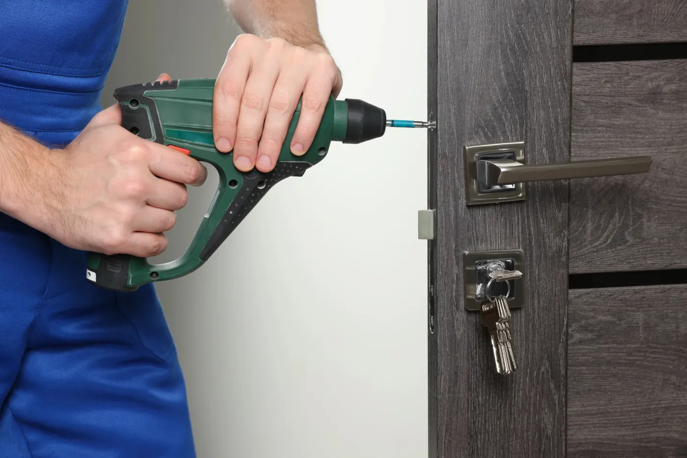 Serrurier vissant une serrure de sûreté sur une porte d'un logement muriautin